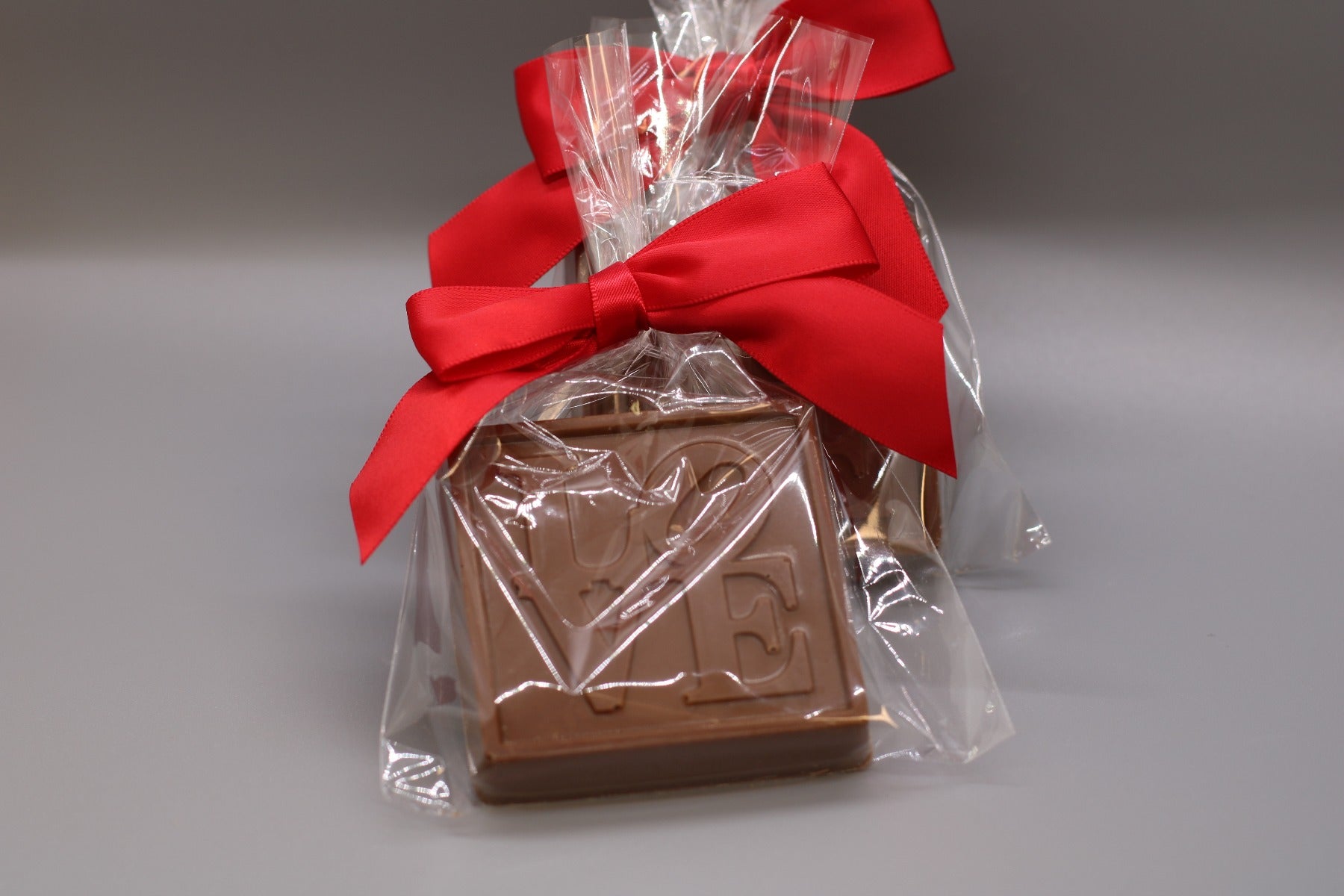 Philadelphia Milk Chocolate Love Statue in clear packaging tied with a red ribbon