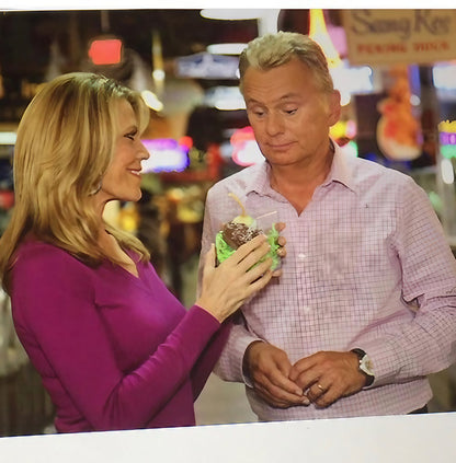 Vanna White and Pat Sajak hosts of The Wheel Of Fortune standing in front of a Muellers Chocolate In Philadelphia holding a chocolate covered onion