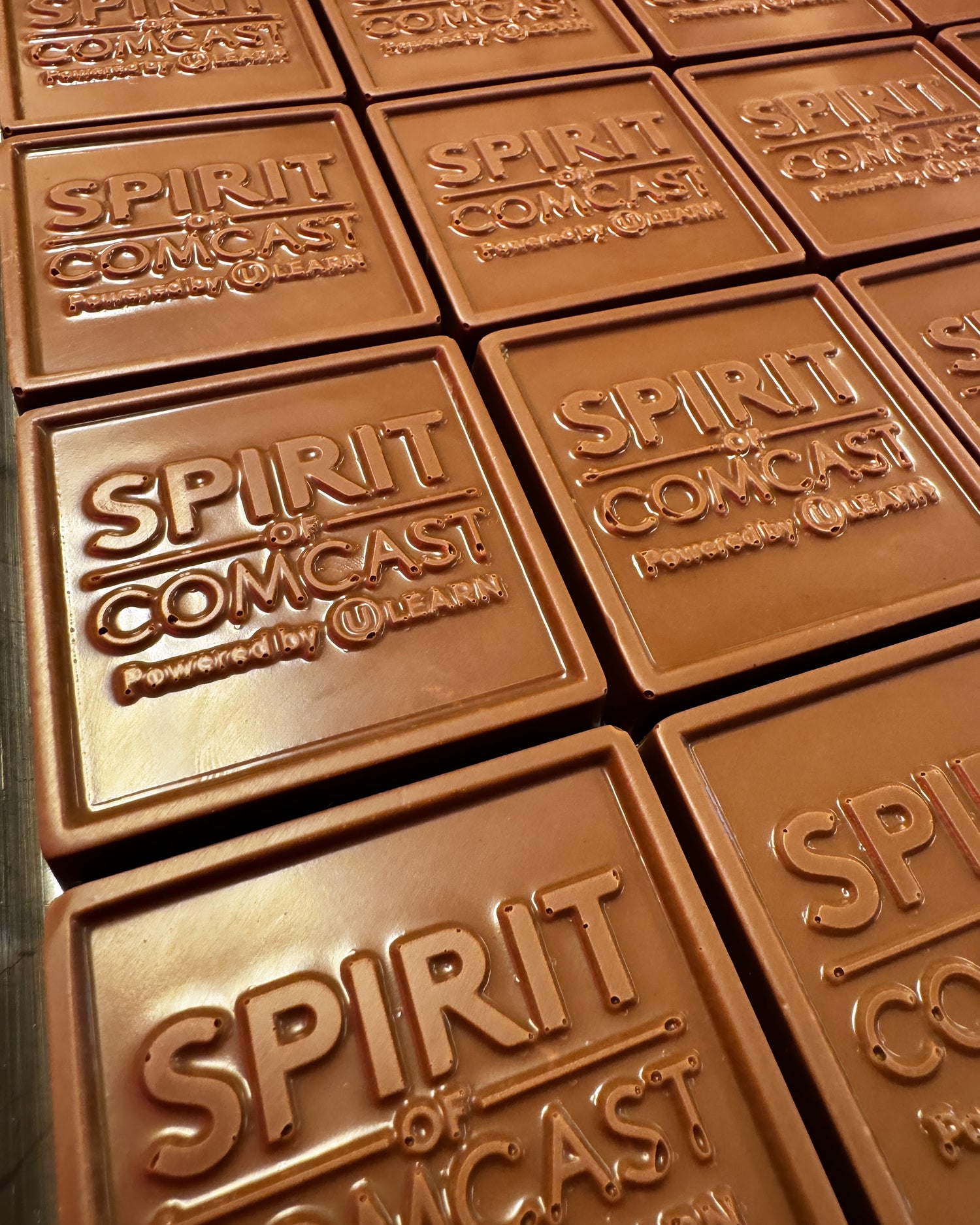 Custom chocolate molds featuring the Comcast logo – personalized corporate chocolate bars made by Mueller Chocolate Co.